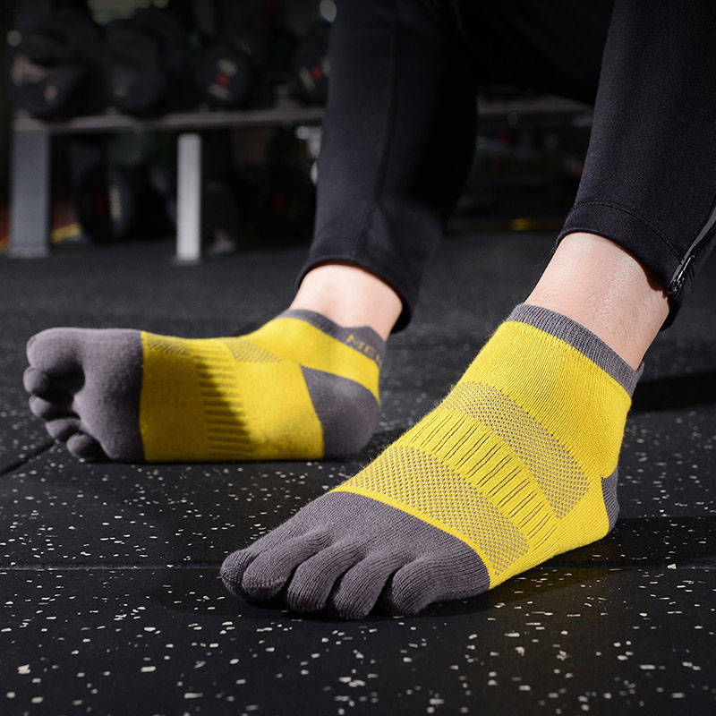 Person wearing yellow and gray toe socks in a gym setting.
